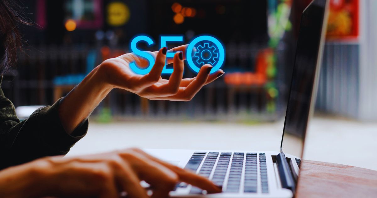 Pessoa usando notebook enquanto segura a palavra SEO, representando otimização de sites para o Google