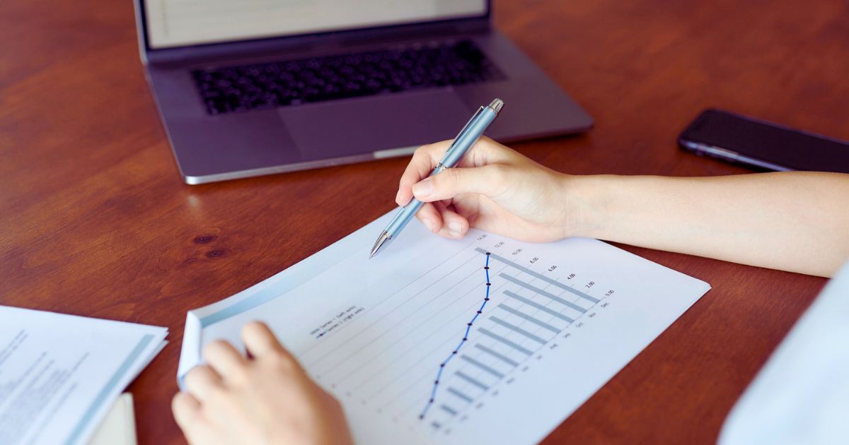 Pessoa com caneta na mão analisando gráfico de crescimento acelerado sobre a mesa, representando estratégias de growth hacking para empreendedores digitais