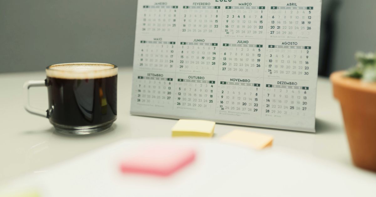 Calend�rio sobre uma mesa com x�cara de caf� e objetos de trabalho, representando planejamento e frequ�ncia de postagem no YouTube.