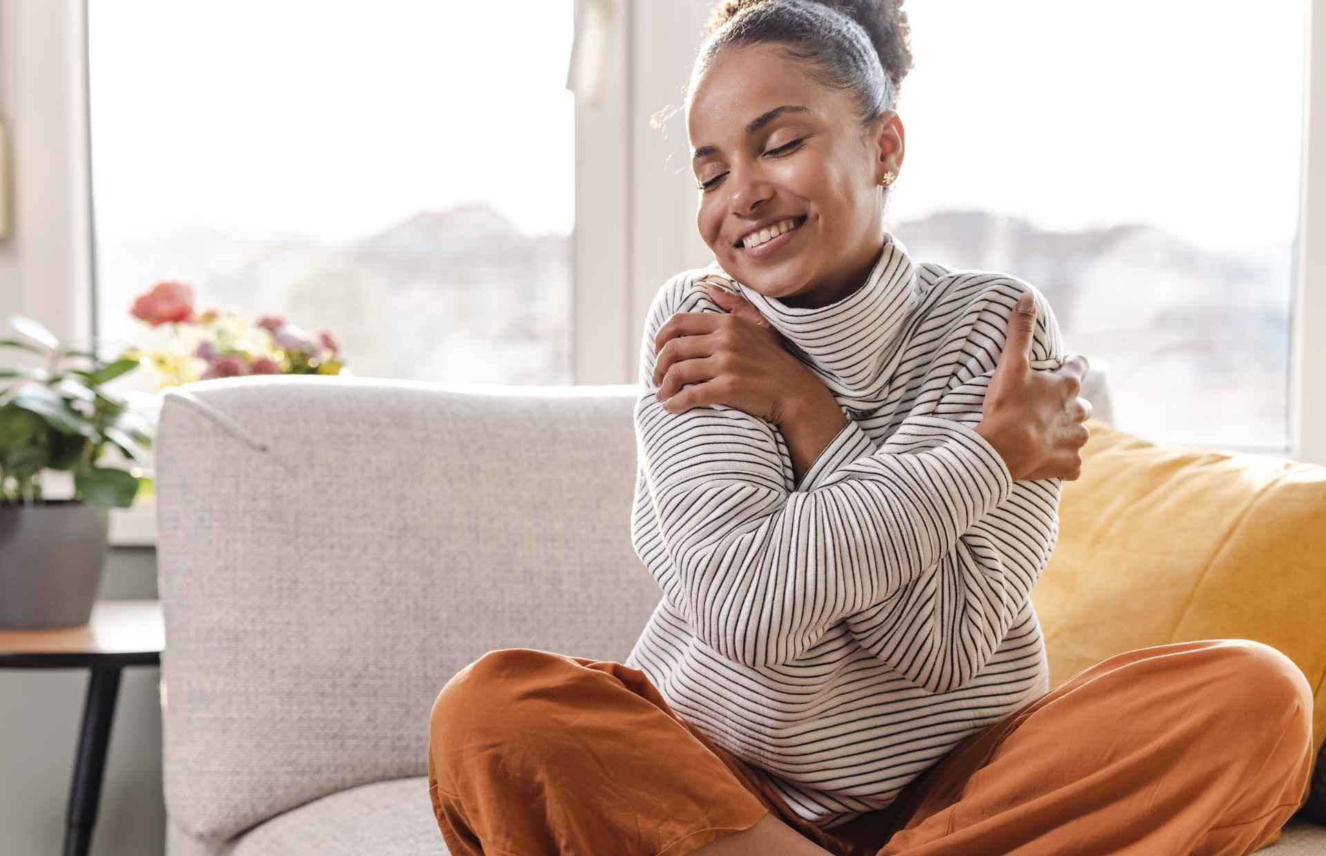 Woman hugging herself on couch