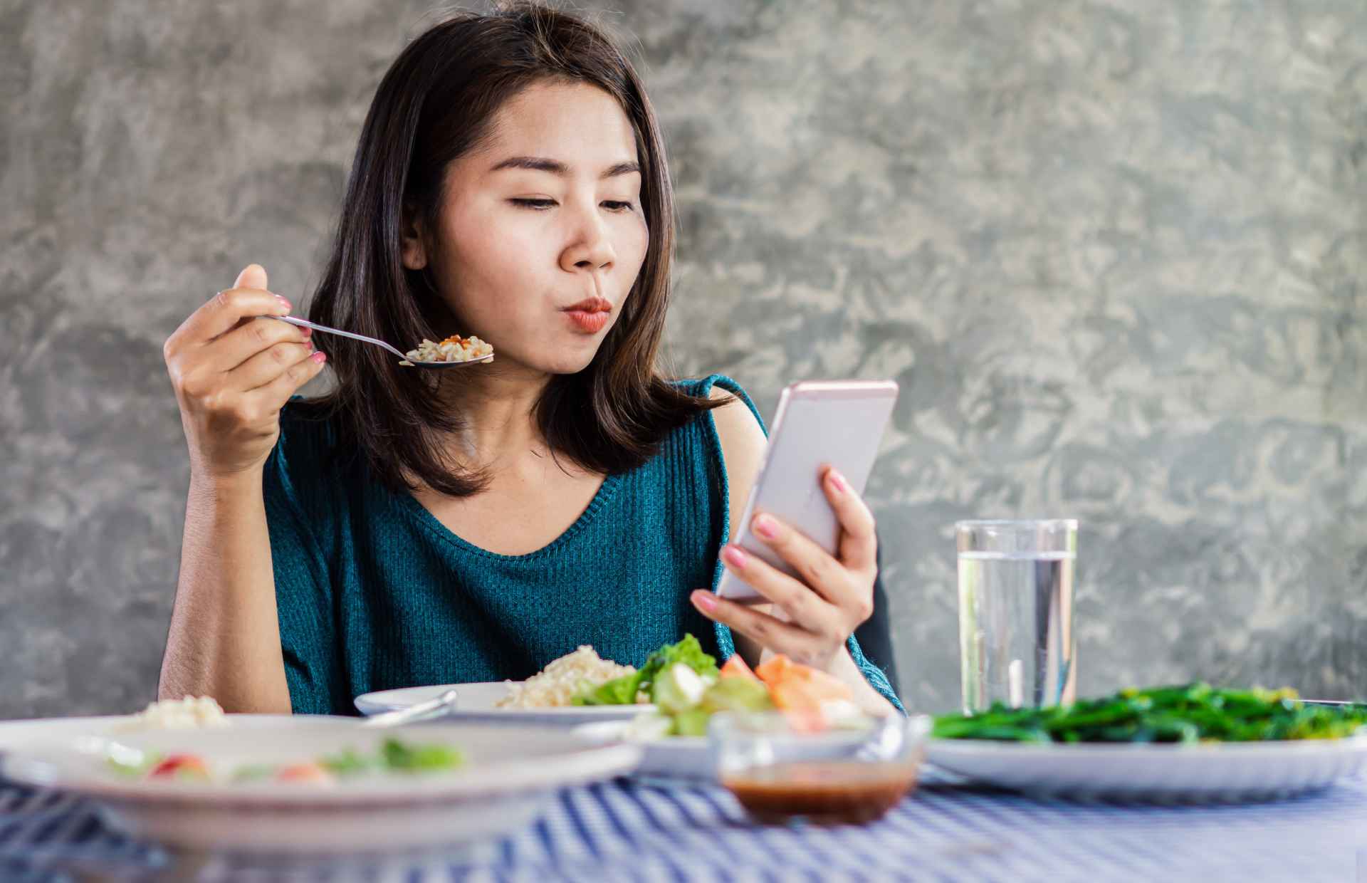 woman looking at phone screen whilst eating