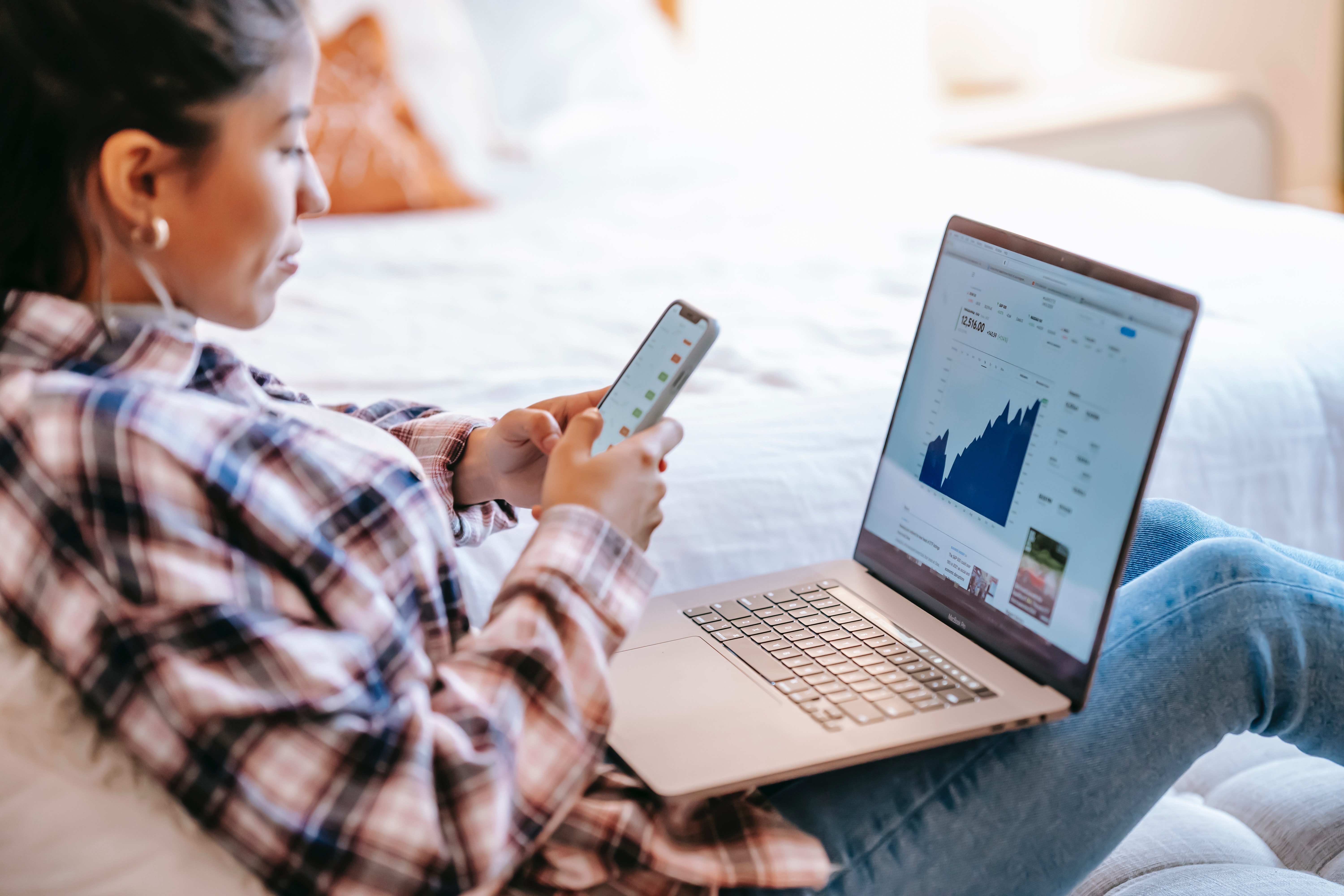 Finde den besten Broker für deine Anlagestrategie: Tipps und Tricks eine Frau handelt Aktien am Smartphone