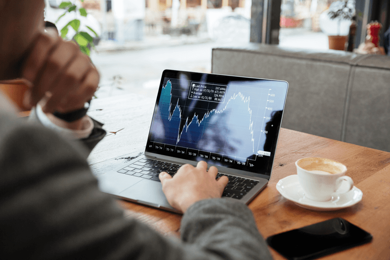ein Mann sitzt vor seinem Laptop und sieht ein Chart mit fallendem Kurs